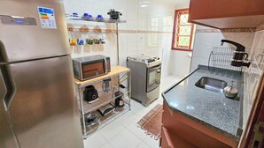 Μια μικρή, λειτουργική κουζίνα με ψυγείο, φούρνο μικροκυμάτων, κουζίν α και νεροχύτη.