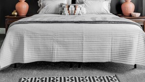 Een moderne slaapkamer met een groot bed, twee bedlampjes, een plafondventilator en een opvallend kunstwerk aan de muur.
