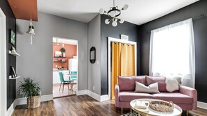Een moderne woonkamer met een roze bank, een rond bijzettafeltje en een vloerkleed met een patroon.