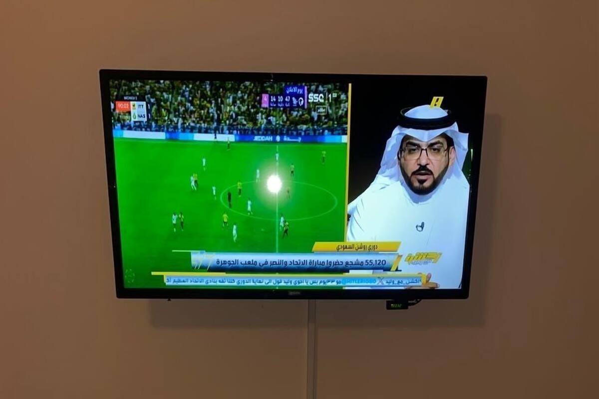 A television mounted on a wall displaying a sports event.