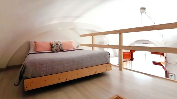 A bedroom with a wooden bed, a view of the outside, and a balcony. - [Domus Helianthus]Cozy Loft, Wifi,Parking (Salandra)