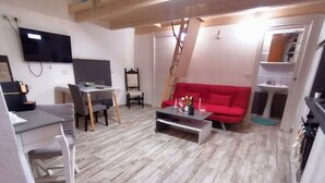 A living room with a red sofa, a coffee table, a TV mounted on the wall, and a wooden staircase. - [Domus Helianthus]Cozy Loft, Wifi,Parking (Salandra)