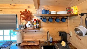 Een kleine keuken met houten wanden, een spoelbak en verschillende keukengerei.