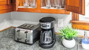 A kitchen with wooden cabinets, a toaster, a coffee maker, and a potted plant.