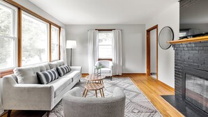 A modern living room with a fireplace, a sofa, a chair, and a round table.
