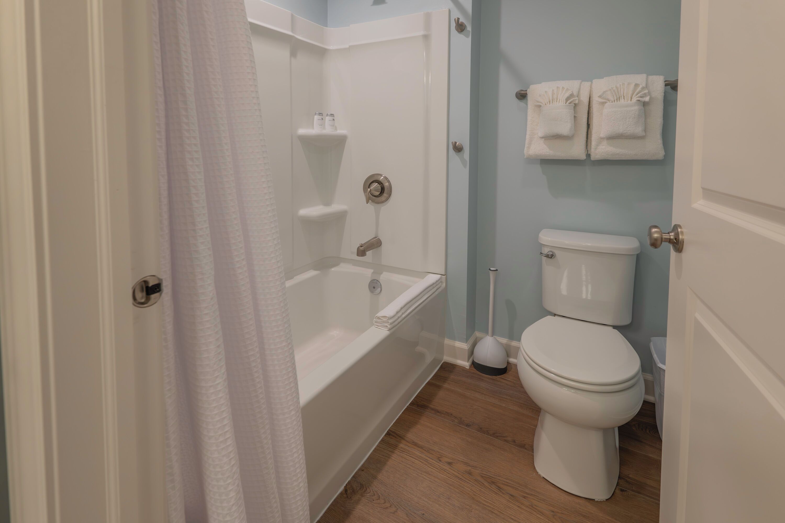 A bathroom with a bathtub, toilet, and shower curtain.