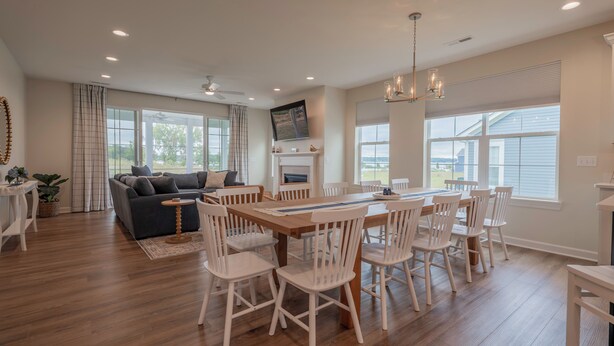 A spacious living room with a large wooden dining table surrounded by white chairs, a grey sofa, and a fireplace. - 2728 Harbor Court (Delavan)