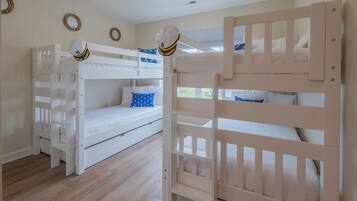 A room with two bunk beds, a white ceiling, and a wooden floor.
