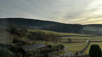 Un paisaje rural con edificios de piedra, un camino de tierra y mesas de picnic.