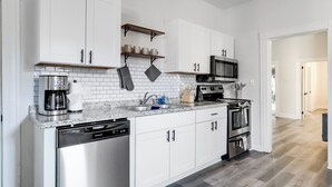 A modern kitchen with white cabinets, a built-in oven, a microwave, and a dishwasher.