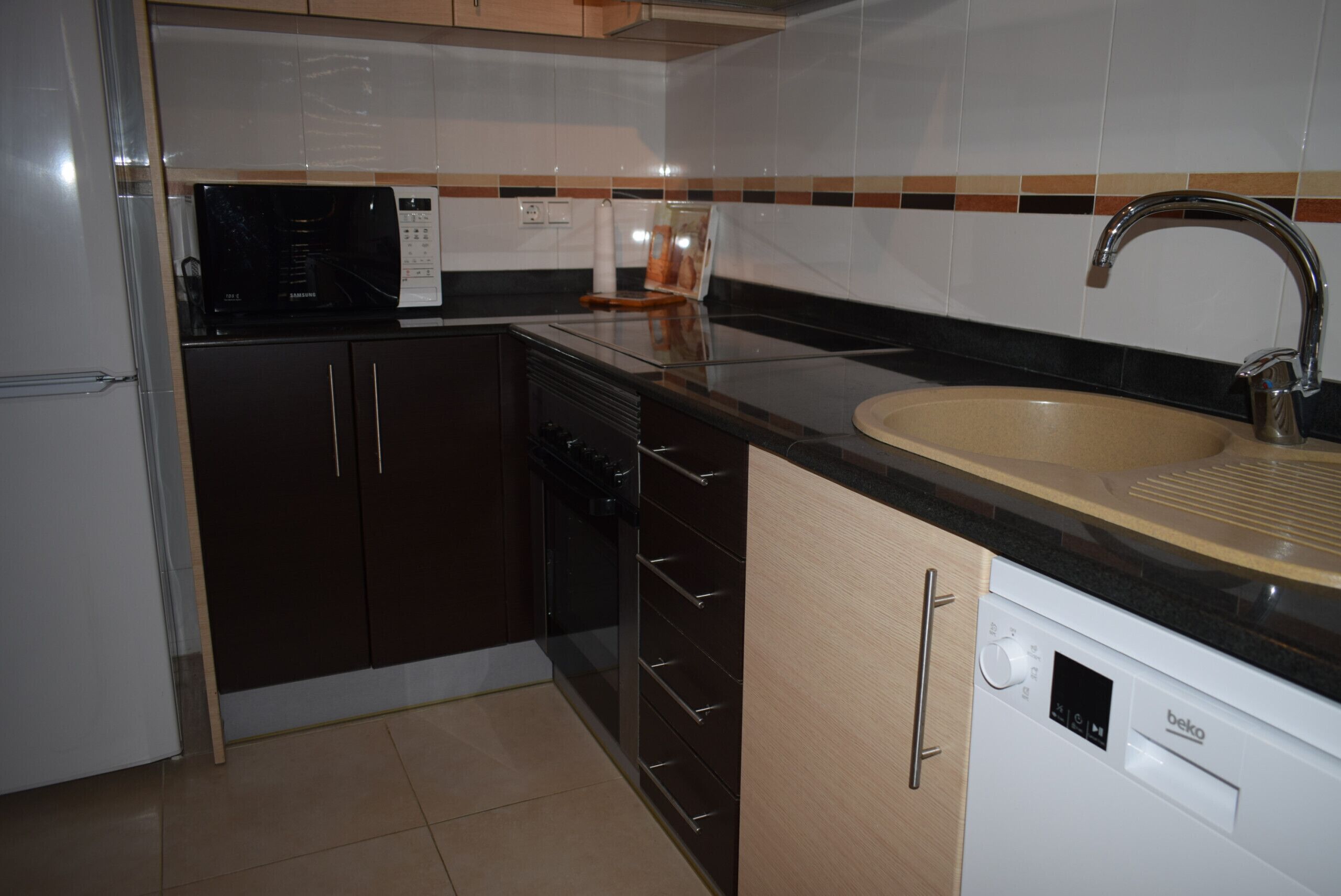 Una cocina equipada con microondas, estufa, lavaplatos y pileta.