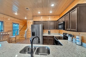Eine moderne Küche mit Holzwänden, Granit-Arbeitsplatten, Edelstahlgeräten und einem eingebauten Backofen.