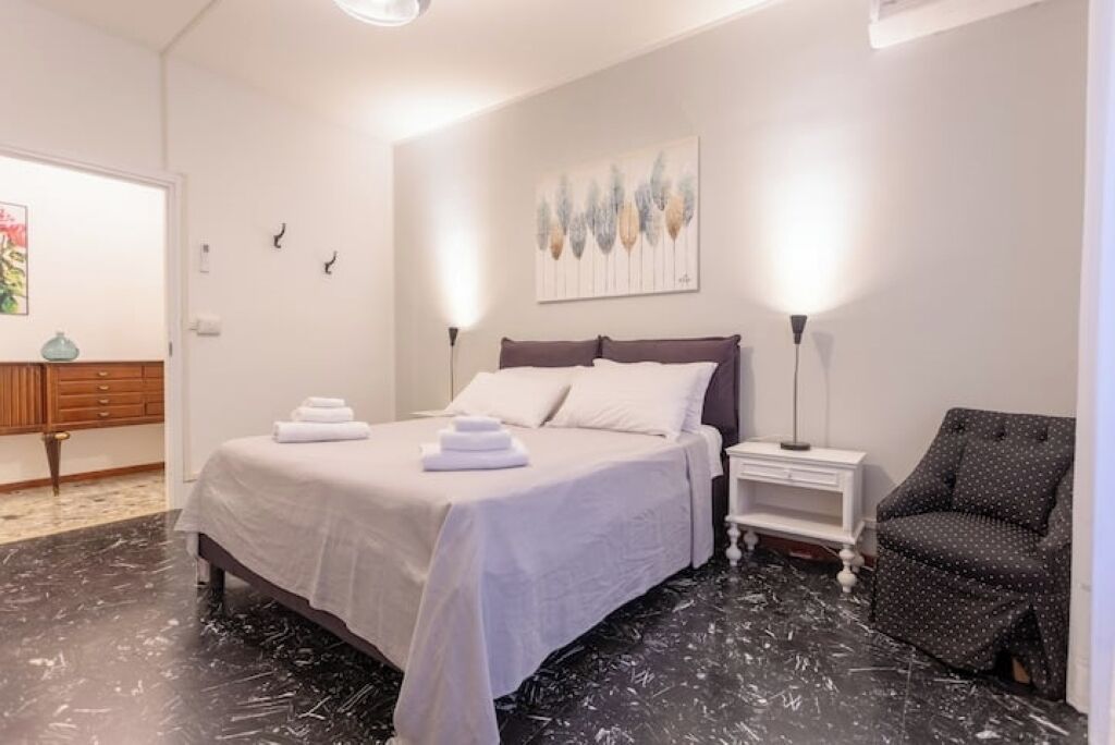 Une chambre d’hôtel avec un lit, des tables de chevet, une chaise et un tableau au mur.