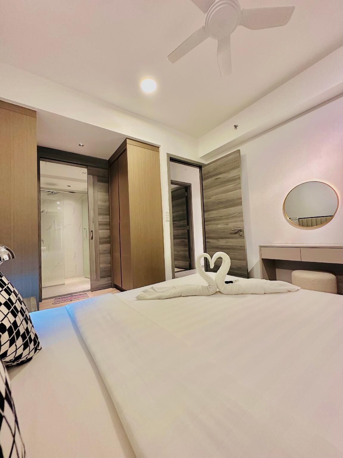Une chambre d’hôtel avec un lit, un ventilateur de plafond, un miroir rond et une armoire.