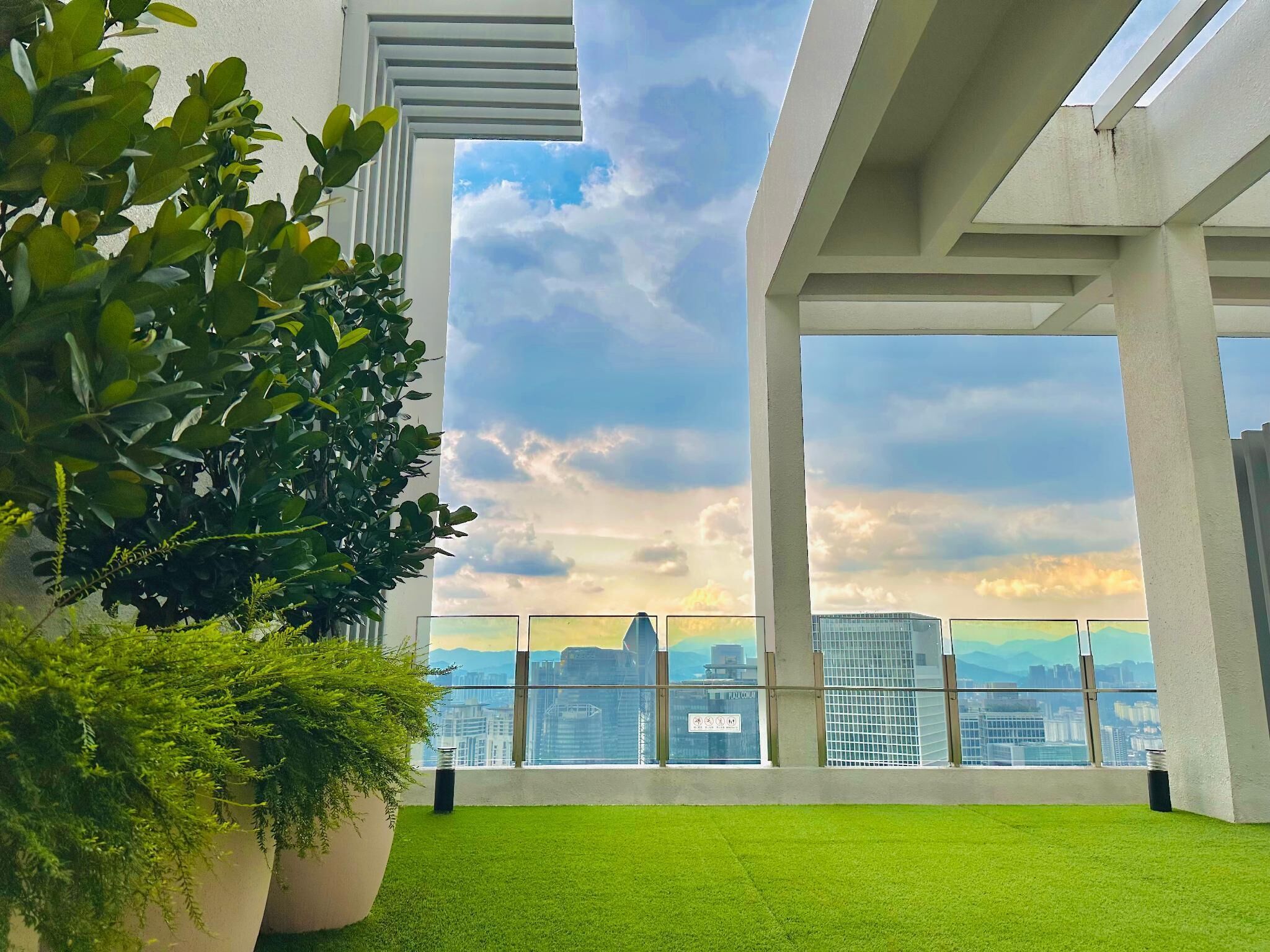 A modern interior with large windows, green artificial grass, and potted plants.