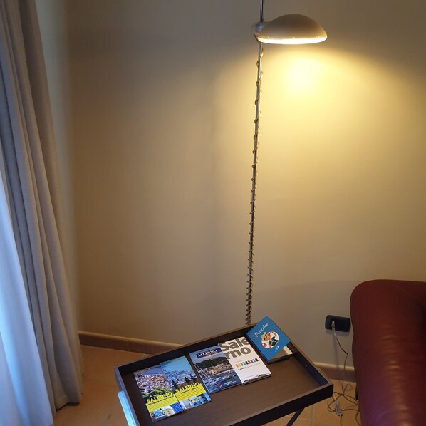 Una habitación con una pequeña mesa mostrando mapas turísticos y una lámpara colgando del techo.