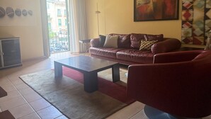 Un salon avec un canapé en cuir, une table basse et un tableau accroché au mur.