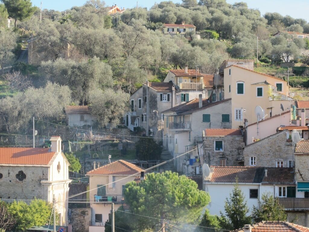 A hillside village with traditional stone buildings, a church, and a mix of residential and possibly commercial structures.