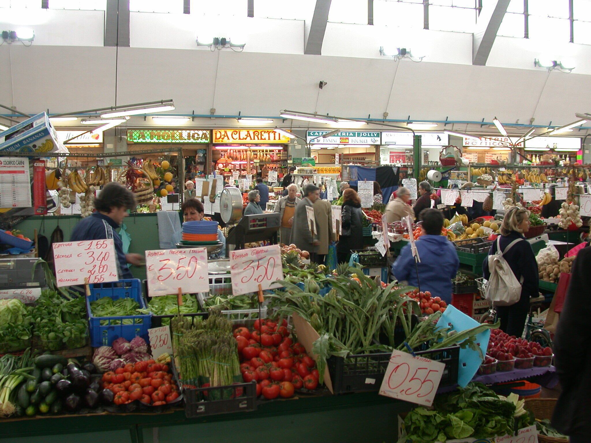 A bustling indoor market with various stalls selling fresh produce and other goods.