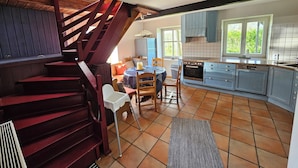 Una cocina con comedor, una escalera y vistas a zonas verdes.