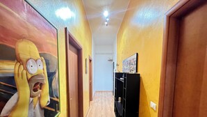 Un pasillo con paredes amarillas, puertas de madera y un mueble negro.