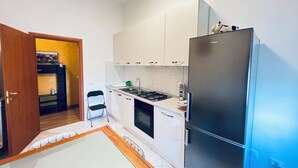 Cocina compacta con armarios blancos, un refrigerador de acero inoxidable, una estufa a gas y un lavamanos pequeño.