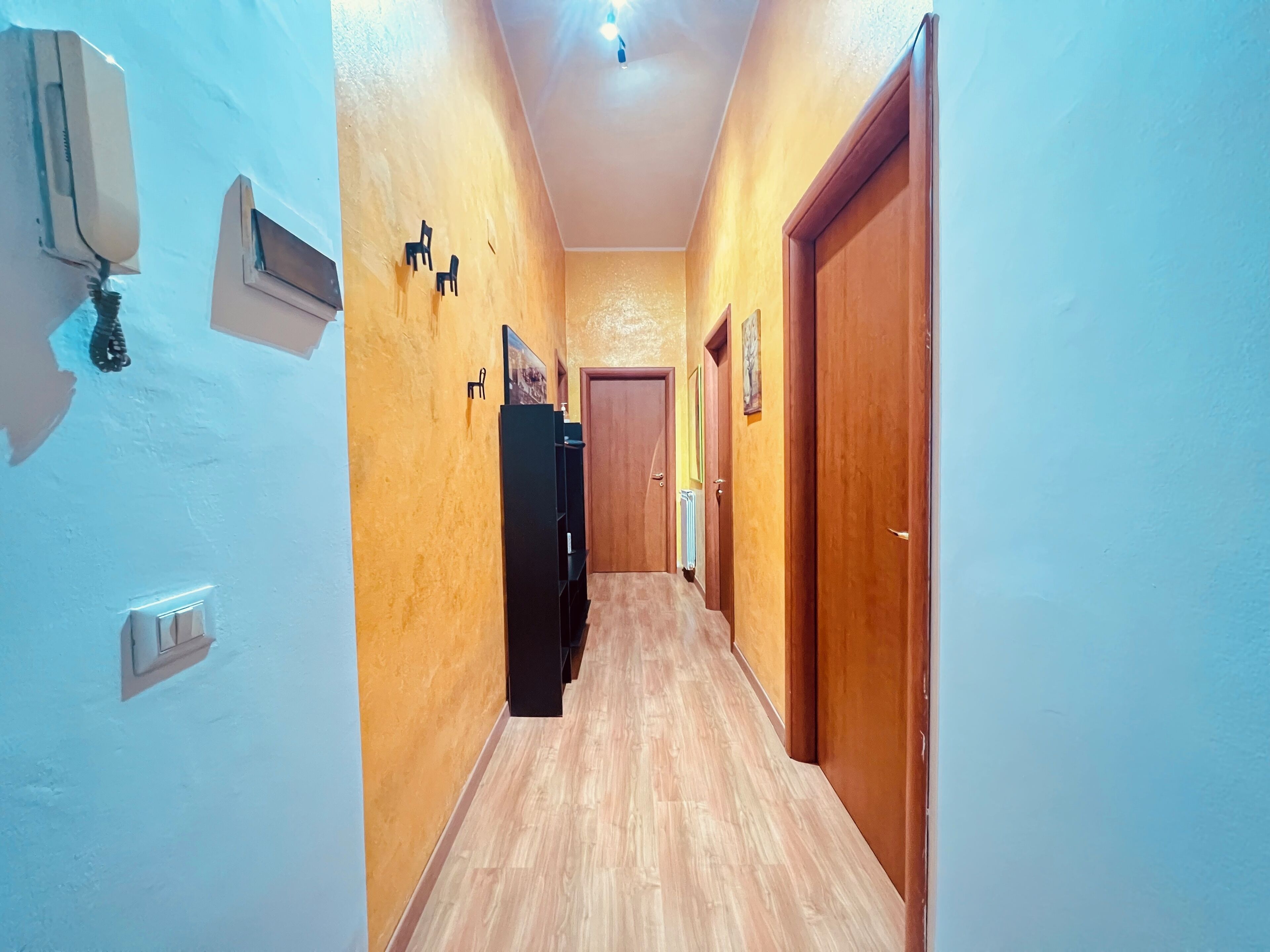 A narrow hallway with wooden flooring, a ceiling fan, and a wall-mounted air conditioning unit.