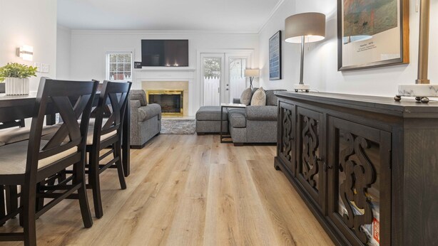 A modern living room with a fireplace, a dining area with wooden chairs, a sofa, and a TV mounted on the wall. - Two King Suites~ Downtown Rome~Walk to Broad (Rome)