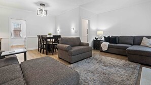 A modern living room with a grey sofa set, a dining table with chairs, and a large rug. - Two King Suites~ Downtown Rome~Walk to Broad (Rome)