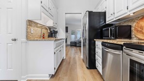 A modern kitchen with white cabinetry, stainless steel appliances, and a granite countertop. - Two King Suites~ Downtown Rome~Walk to Broad (Rome)