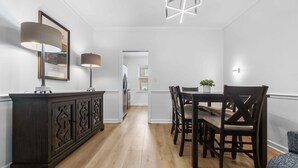 A dining area with a dark wood cabinet, two wall-mounted lamps, and a table with chairs. - Two King Suites~ Downtown Rome~Walk to Broad (Rome)