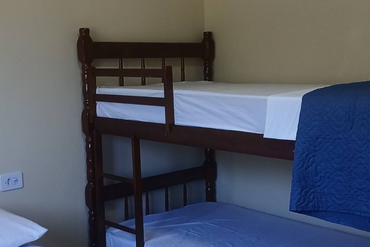 Une chambre avec des lits superposés, un lit simple et un mur blanc muni d’une prise de courant.