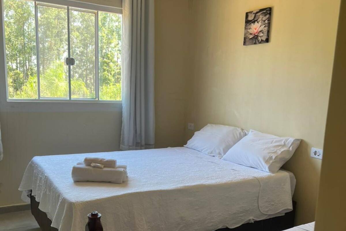 Une chambre à coucher avec un lit, une fenêtre avec des rideaux et un tableau accroché au mur.