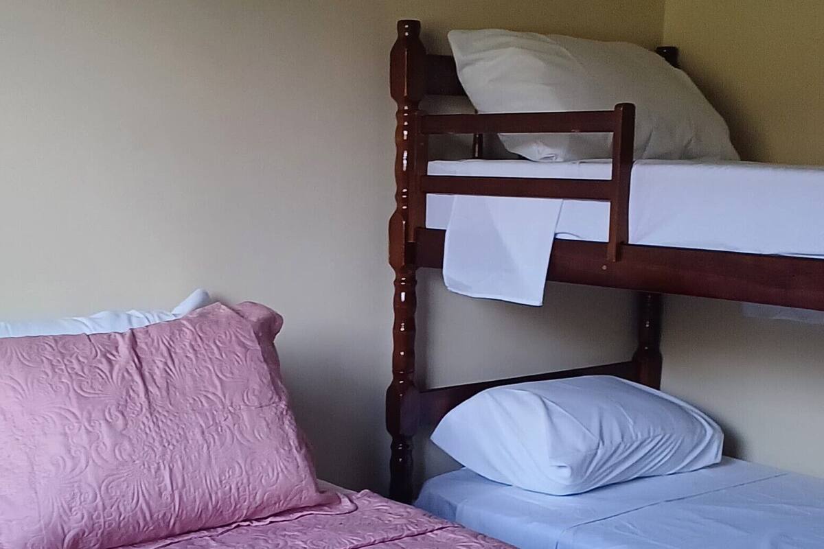 Une chambre avec un lit simple, un lit superposé et une petite table.
