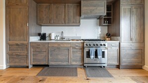 A kitchen with wooden cabinets, a stainless steel stove, and a white tiled backsplash.