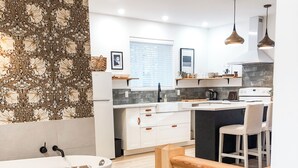Una cocina moderna con gabinetes blancos, una isla central e iluminación colgante.