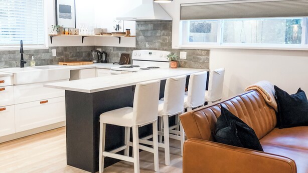Una cocina moderna con armarios blancos, una isla central e iluminación colgante.