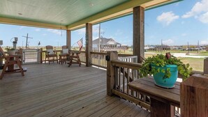 Un espace extérieur abrité doté d’un plancher en bois, d’une rambarde en bois et offrant une vue sur un bâtiment et un paysage.