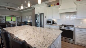Une cuisine moderne dotée de plans de travail en granit, d’appareils électroménagers en acier inoxydable et de meubles blancs.