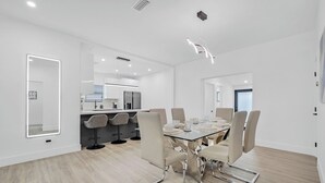 A modern dining area with a glass table, six chairs, and a kitchen in the background. - Design Dist Living:Pool,Basketball CourtandNespresso (Miami)