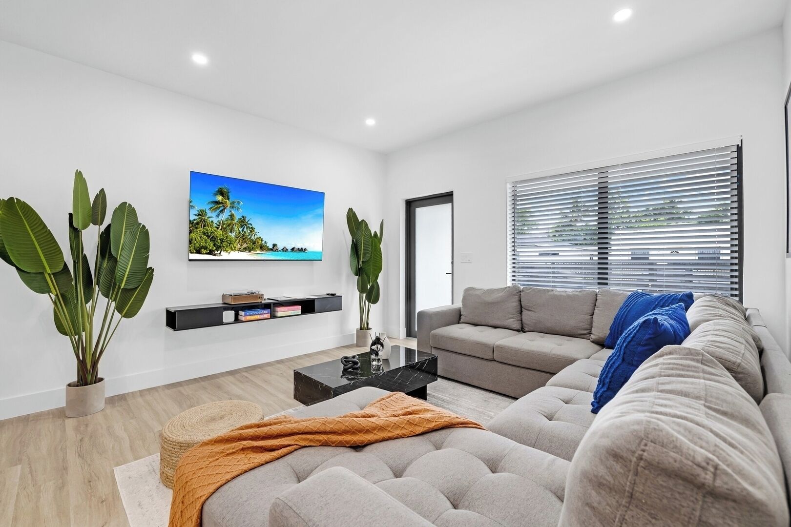 A modern living room with a grey sofa, a coffee table, and a TV mounted on the wall.