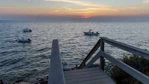 A wooden dock extending into calm waters with two boats anchored. - Bay Views and Panoramic Sunsets! (Eastham)