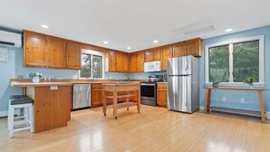 A modern kitchen with wooden cabinets, stainless steel appliances, and a central island. - Bay Views and Panoramic Sunsets! (Eastham)