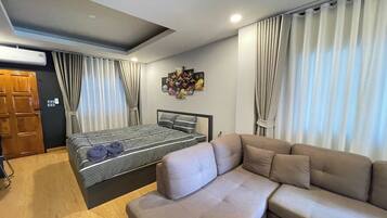 A bedroom with a bed, a sofa, a wall-mounted artwork, and a ceiling light.