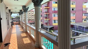 A corridor with columns, a balcony with a metal railing, and a view of colorful buildings. - Marin House Pattaya (Pattaya)