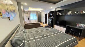 A modern bedroom with a bed, a TV, and a shelf with various items. - Marin House Pattaya (Pattaya)