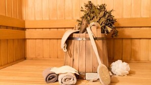 A wooden sauna with a wooden bucket containing a towel, a brush, and dried plants. - Oas Finnerödja (Finnerödja)