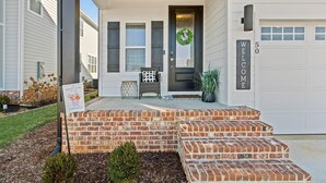 A house with a brick porch, a welcome sign, and a wreath on the door. - Gorgeous Lake House in Twin Creeks - Marina Side (Winchester)