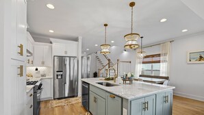 A modern kitchen with a central island, stainless steel appliances, and pendant lighting. - Gorgeous Lake House in Twin Creeks - Marina Side (Winchester)