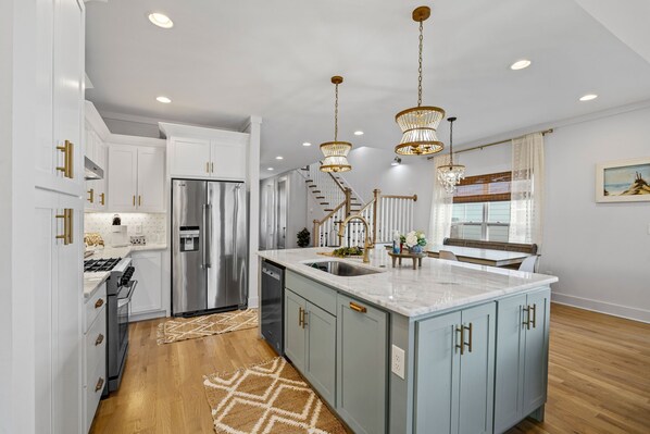 A modern kitchen with a central island, stainless steel appliances, and pendant lighting.
